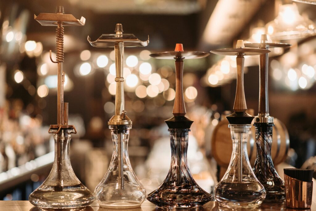 pexels-photo-7518749-7518749 A collection of elegant hookahs displayed on a bar counter, accented by warm bokeh lights.