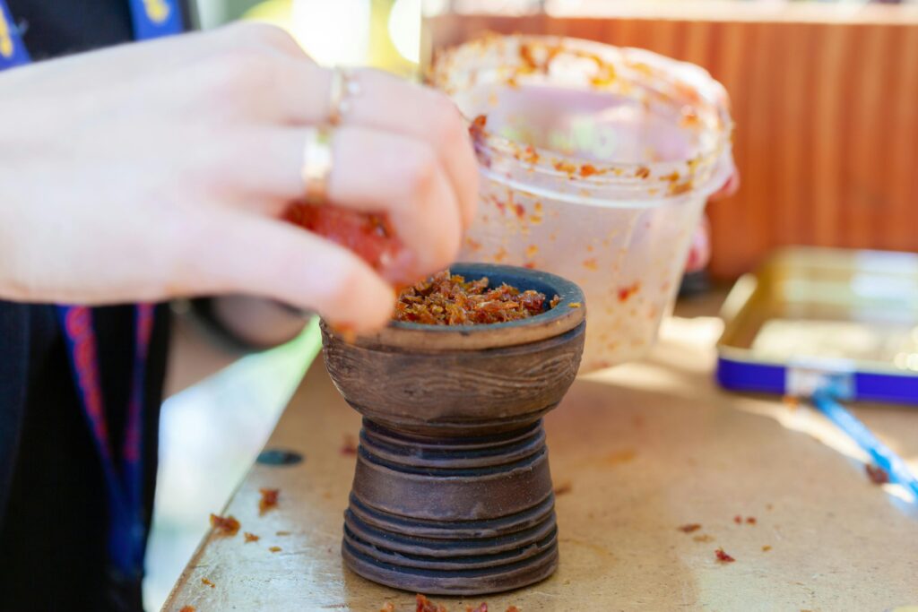pexels-photo-8250689-8250689 A detailed close-up of a hand preparing a hookah bowl with traditional tobacco mix.